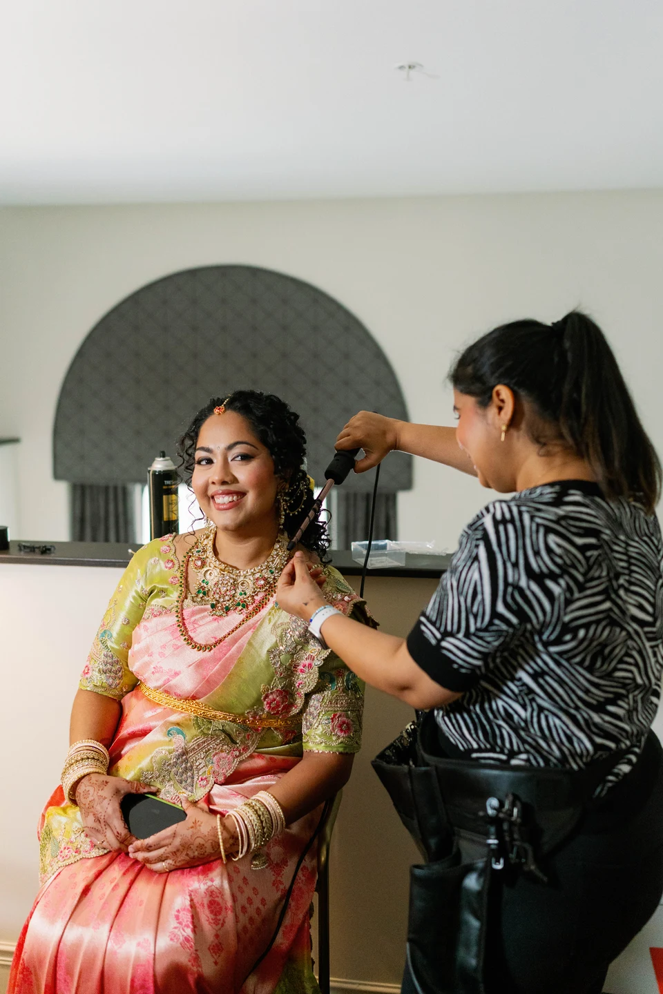 Amulya styling a bride’s hair as she gets ready in a pink silk saree