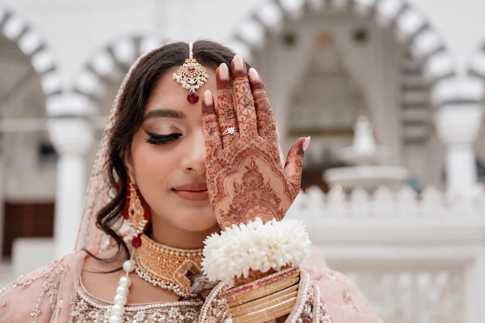 Bride showing her henna beside softly defined bridal eye makeup