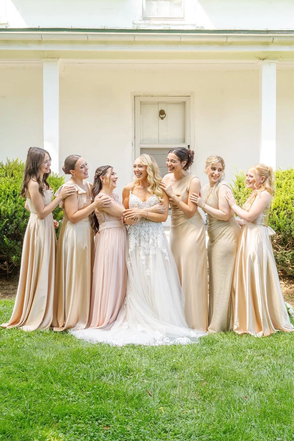 Bride and bridesmaids in pastel dresses gathered on the lawn