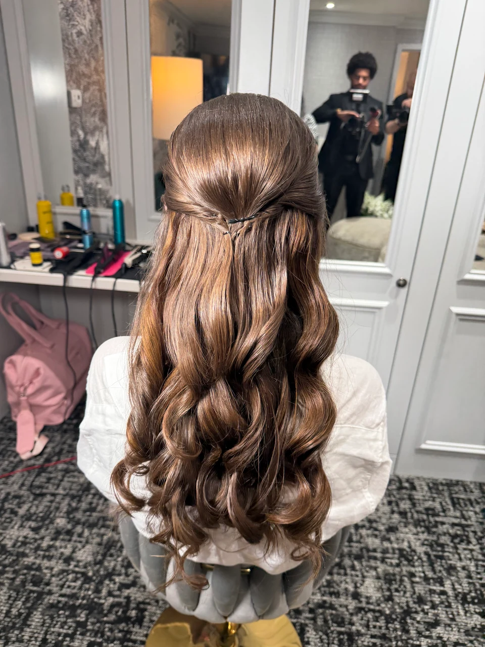 Back view of a half-up hairstyle with loosely pinned sections and cascading brown waves