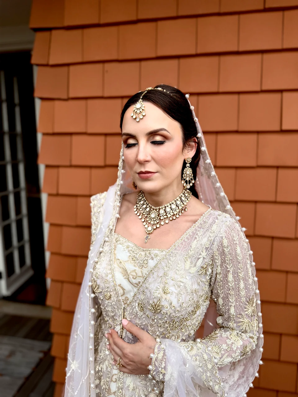 Bridal portrait with a pale embroidered dupatta, pearl jewelry and softly defined makeup
