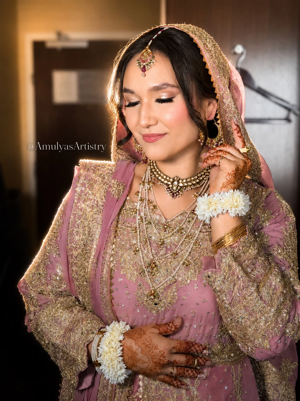 Bride with rose-toned makeup, gold jewelry and a pink dupatta