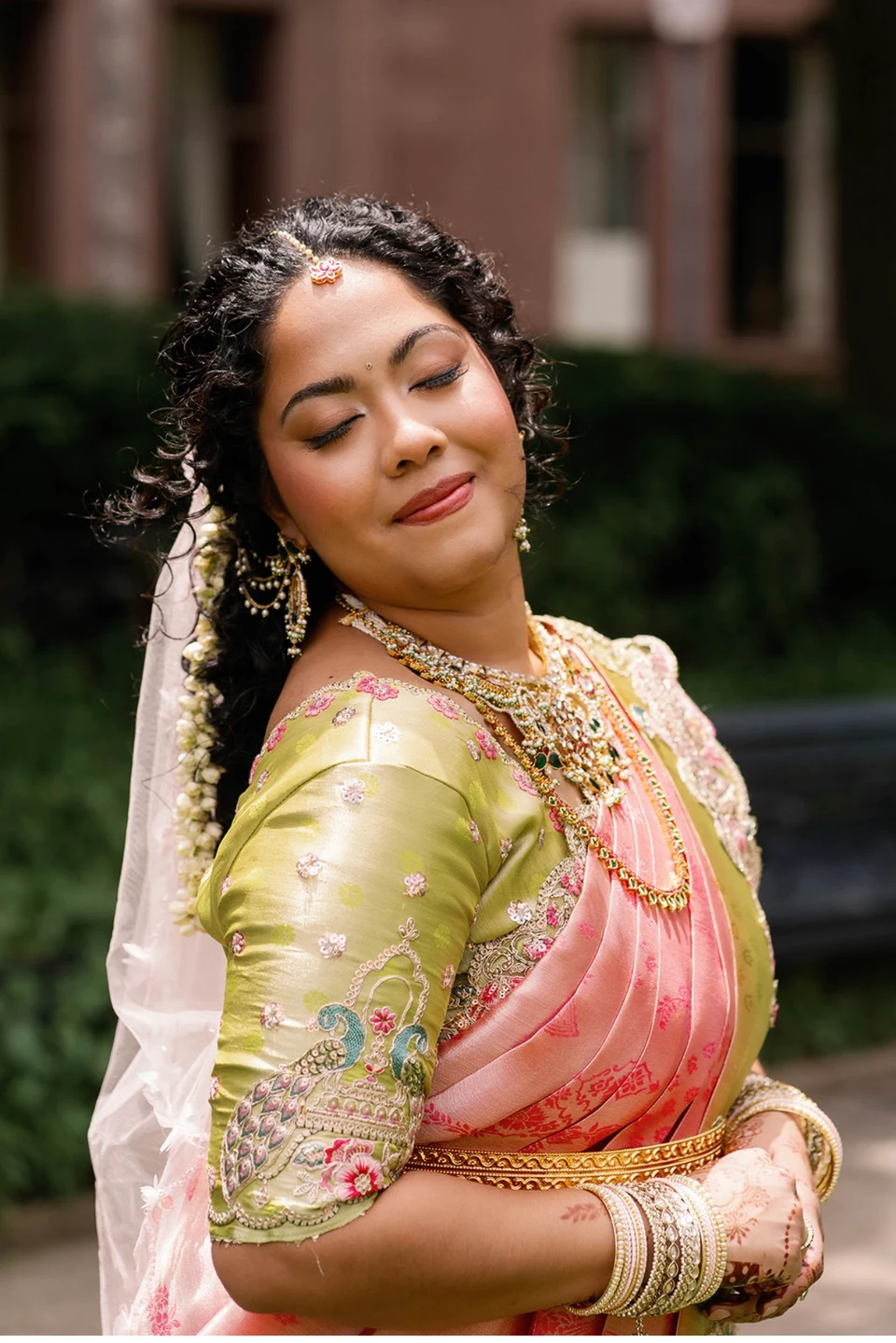 Bride in a pink saree with eyes closed to show her soft eye makeup